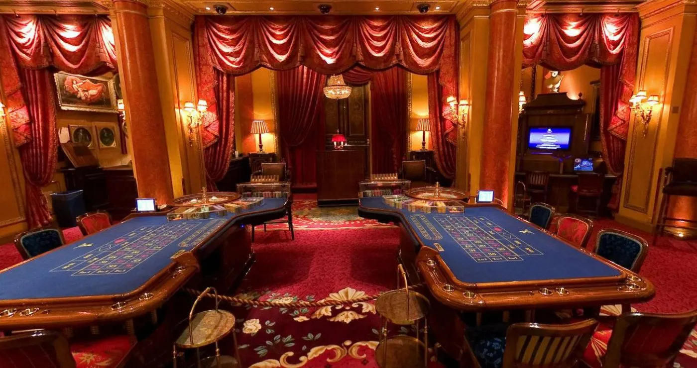 A casino room with a roulette table and a chandelier